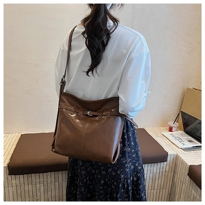 Macro shot of large vintage brown shoulder bag with decorative stitching and metal buckle