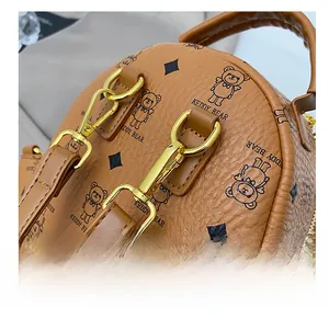 Detailed view of the gold-tone metal hook and textured leather strap of the brown handbag
