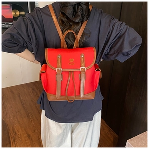 Detailed back view of vintage red canvas backpack with floral embroidery on female model