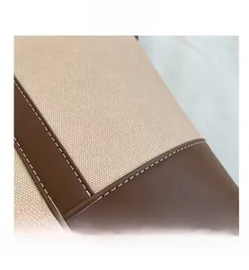 Nahaufnahme von beigem Canvas und braunem Leder mit Ziernähten an einer Schultertasche