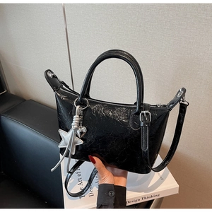 Dettaglio della borsa hobo nera lucida con ciondolo a stella d'argento e zip metallica
