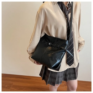 Close-up of black PU leather bucket bag with metal buckle strap and preppy style
