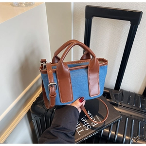 Detail of mini denim patchwork tote bag with brown leather handles and adjustable strap