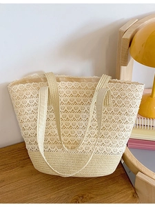 Large beige woven straw tote bag with geometric cutout patterns for summer beach travel
