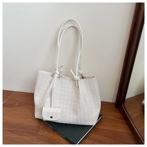 Detailed close-up of a white woven tote bag with a small pouch and knot leather handle