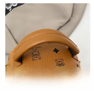 Detail of premium brown pebble leather backpack featuring teddy bear print and gold zipper