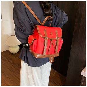 Close-up of red nylon backpack with brown PU leather trim and heart flower embroidery