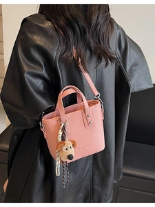 Pink lychee texture bucket bag with plush dog charm and adjustable shoulder strap