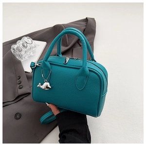 Detail of teal pebble leather bowling bag featuring a silver whale charm and dual handles