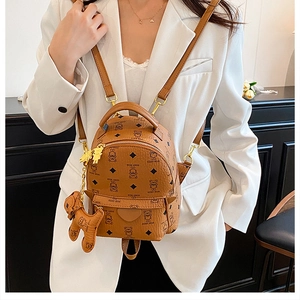 Detail of brown faux leather mini backpack with bear pattern and matching plush charm