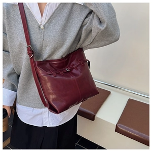 Detail of burgundy leather shoulder bag with decorative strap buckle and adjustable strap