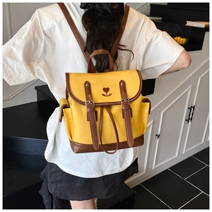 Detail of yellow nylon backpack with embroidered heart and brown leather straps