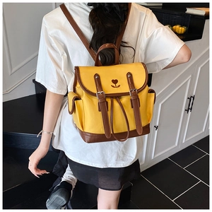 Close-up of yellow and brown two-tone backpack featuring heart floral embroidery and leather straps