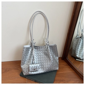 Close-up of silver woven tote bag texture with slim straps and small matching pouch