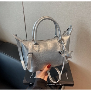 Dettaglio della borsa a pieghe argento metallizzato con ciondoli a cuore e stella