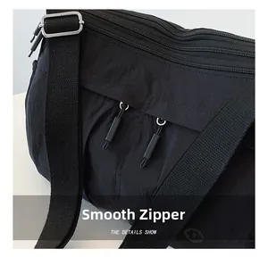 Detail shot of black nylon shoulder bag featuring smooth triple zippers and adjustable strap