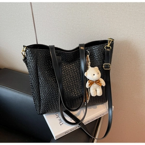 Detail of black woven tote bag with adjustable strap and cute plush bear charm