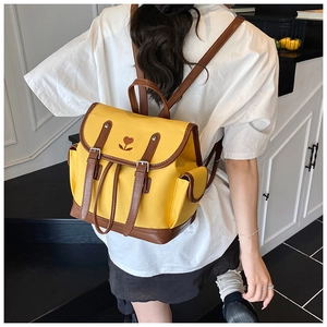 Woman wearing the yellow and brown contrast backpack with floral tulip embroidery detail