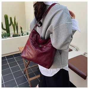 Deep red tote bag worn by a model in a casual setting showing the large capacity and style