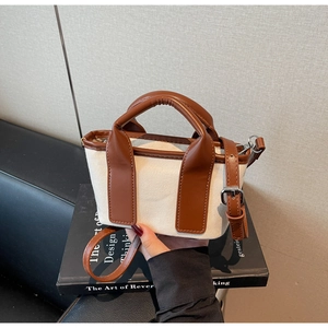 Close-up of canvas crossbody bag with brown leather trim and adjustable shoulder strap
