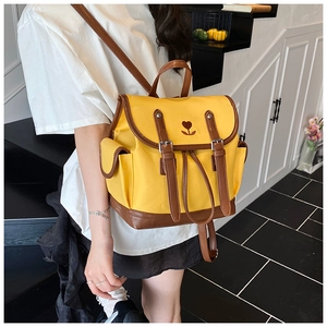 Detail of yellow nylon backpack with brown leather cover and red floral heart embroidery