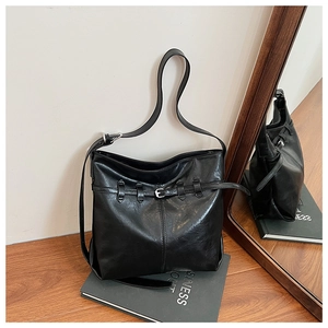 Close-up of black retro tote bag in glossy leather with silver buckle and adjustable strap