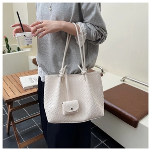 Detail of off-white woven tote bag with knotted handles and matching coin purse