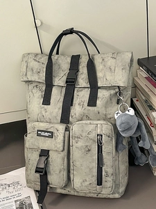 Grey marble roll-top backpack with buckle pocket and frog pendant in lifestyle setting