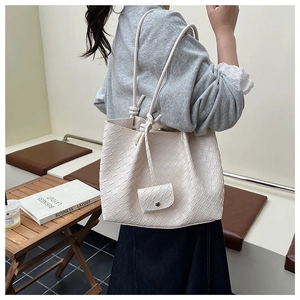 Detailed view of cream woven tote bag with matching pouch shown on a model