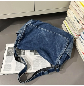 Nahaufnahme einer blauen Vintage-Denim-Umhängetasche mit verstellbarem Gurt im Freien