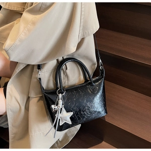 Dettaglio borsa nera a pieghe con ciondoli a stella e cuore indossata da una modella