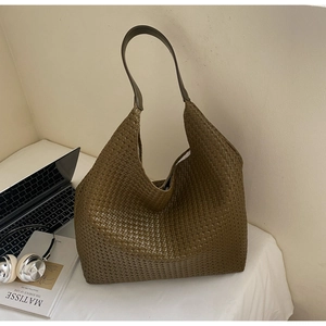 Detail of dark green woven hobo bag with leather handle and matte texture finish