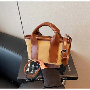 Detail of a vintage canvas tote bag with brown leather handles and a cross-body strap