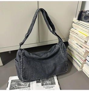 Details einer dunkelgrauen Messenger-Tasche aus gewaschenem Denim mit verstellbarem Gurt