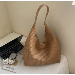 Detail of a large brown woven tote bag featuring a premium leather weave texture