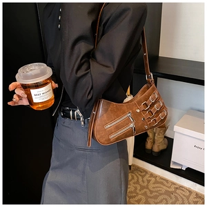 Detailed punk style brown leather bag with metallic zippers and adjustable side buckles