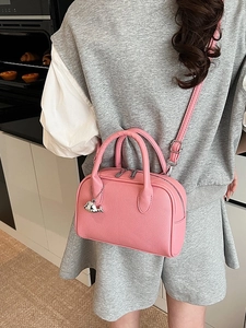 Pink litchi leather bowling handbag with whale charm shown in a lifestyle setting