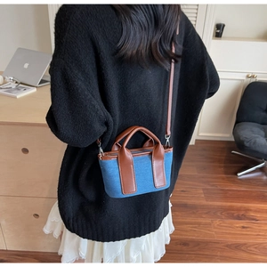 Lifestyle shot of a mini blue denim canvas bag with brown leather handles worn by a model