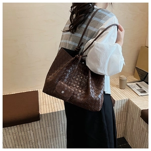 Detail of a large brown woven tote bag with a matching mini pouch and drawstring closure