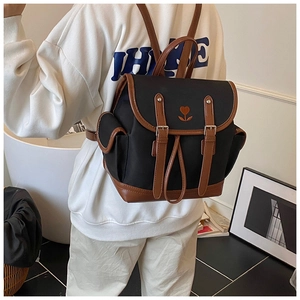 Detail of vintage canvas backpack with brown leather straps and heart embroidery