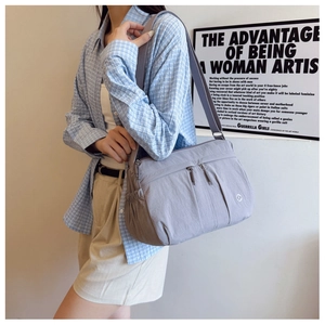Detailed view of lightweight nylon crossbody bag featuring multiple zipper pockets and wide strap