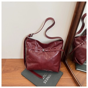 Detail of burgundy vintage shoulder bag with matte leather texture and metal buckle strap