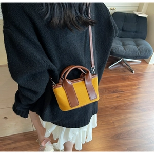 Close-up of yellow canvas mini tote bag with brown leather trim worn by a model