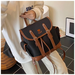 Detail of black nylon backpack with brown leather trim and orange heart flower embroidery