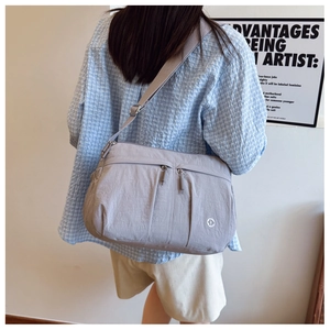 Detail of grey nylon crossbody bag with adjustable strap and multiple zipper pockets