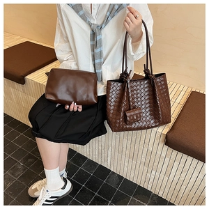 Detail of dark brown woven leather tote bag with knot handle and matching clutch bag