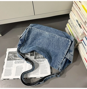 Detail einer Vintage-Messenger-Bag aus gewaschenem Denim mit verstellbarem Gurt und Schnalle