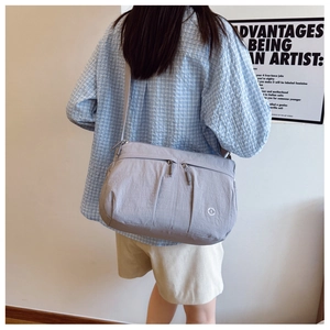 Detail view of gray-purple crossbody bag featuring multi-zipper sections and nylon texture