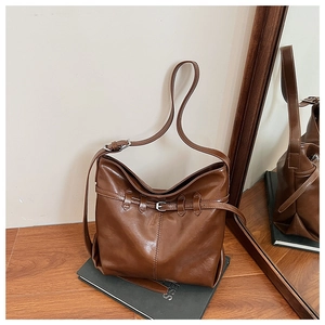 Detailed close-up of brown PU leather shoulder bag with buckle and adjustable strap
