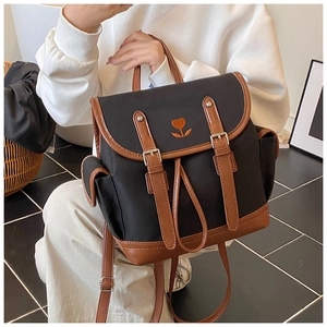 Macro shot of retro black canvas backpack with brown leather trim and heart embroidery
